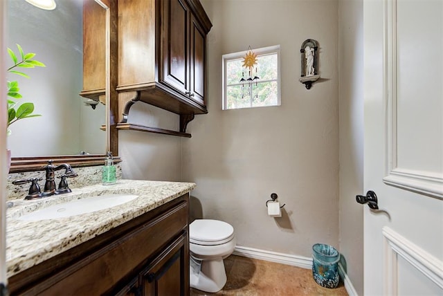 half bath featuring vanity, toilet, and baseboards