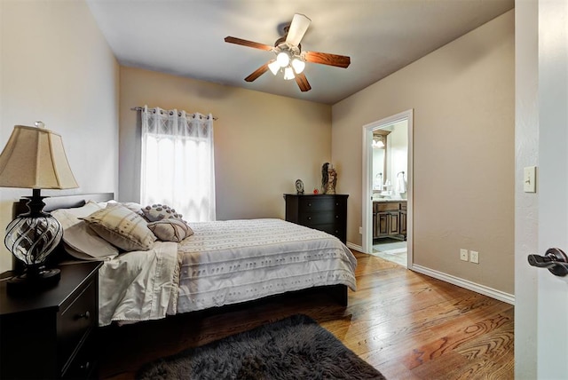 bedroom with a ceiling fan, ensuite bath, baseboards, and light wood-type flooring