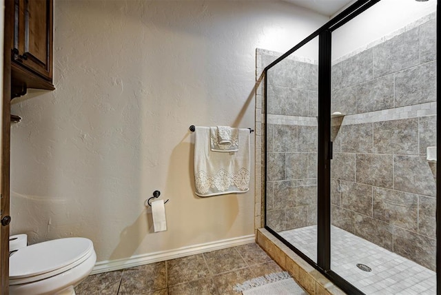 bathroom featuring baseboards, toilet, a stall shower, a textured wall, and tile patterned floors