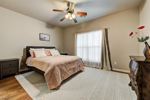 bedroom featuring ceiling fan, wood finished floors, visible vents, and baseboards