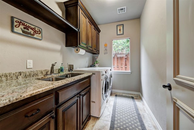 clothes washing area with washing machine and dryer, sink, light tile patterned floors, and cabinets