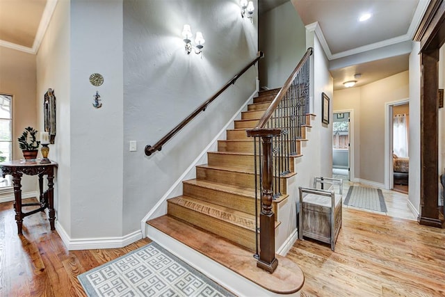 staircase featuring baseboards, wood finished floors, and crown molding