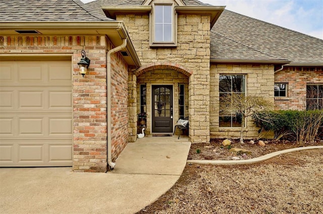 entrance to property with a garage, brick siding, and a shingled roof