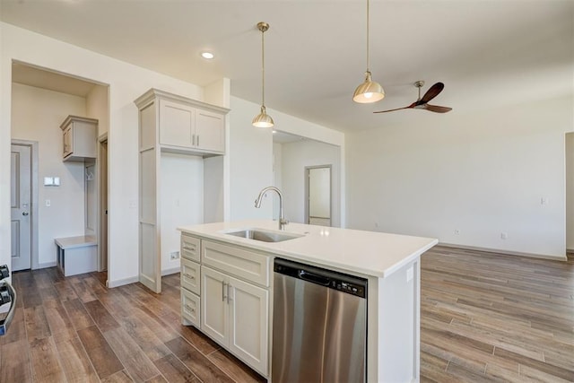 kitchen featuring hardwood / wood-style floors, sink, hanging light fixtures, stainless steel dishwasher, and a center island with sink