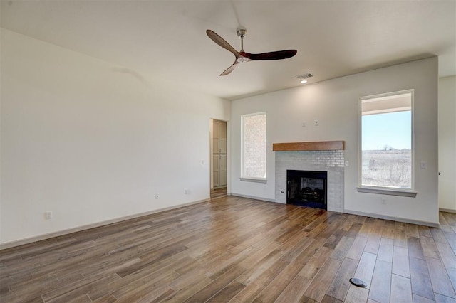 unfurnished living room featuring ceiling fan, hardwood / wood-style floors, and a fireplace