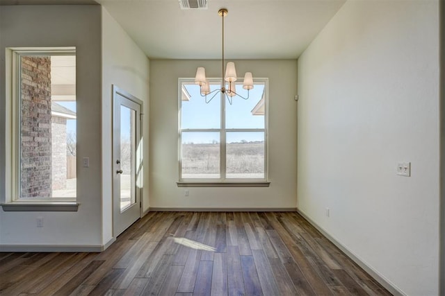 unfurnished dining area with a healthy amount of sunlight, a chandelier, and dark hardwood / wood-style floors