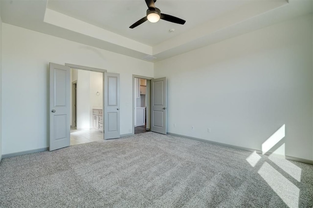 unfurnished bedroom featuring ceiling fan, light colored carpet, and a tray ceiling