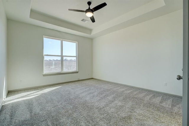 unfurnished room featuring ceiling fan, a tray ceiling, and light carpet