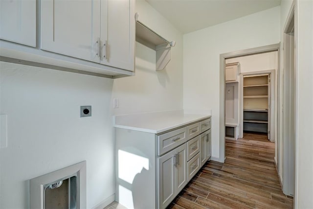 washroom with dark wood-type flooring, cabinets, and electric dryer hookup