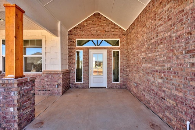 entrance to property featuring a patio and brick siding