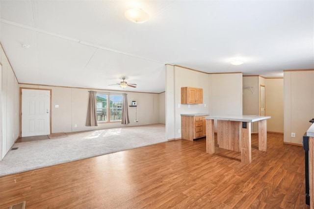 kitchen with ceiling fan, a kitchen island, light wood-type flooring, and a breakfast bar area