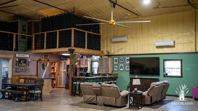 living room with a wall mounted air conditioner, ceiling fan, concrete flooring, and a high ceiling