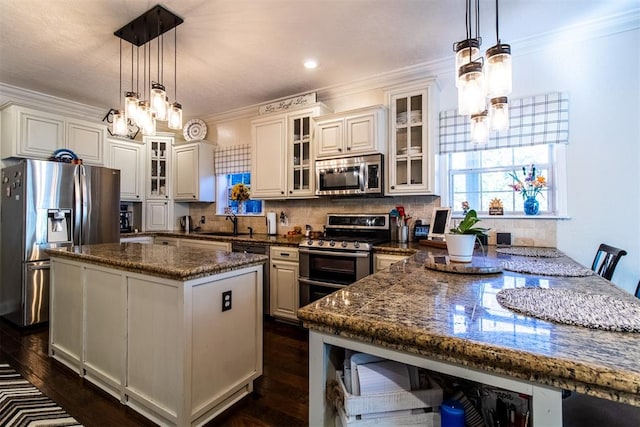 kitchen featuring hanging light fixtures, white cabinetry, stainless steel appliances, and dark stone counters