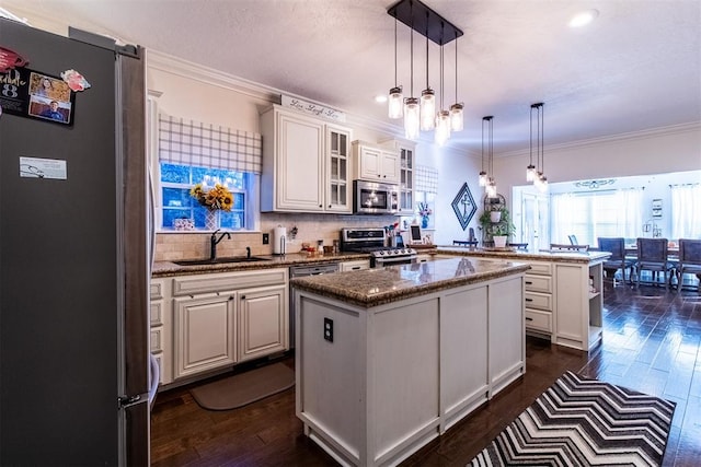 kitchen with white cabinets, a center island, stainless steel appliances, and hanging light fixtures