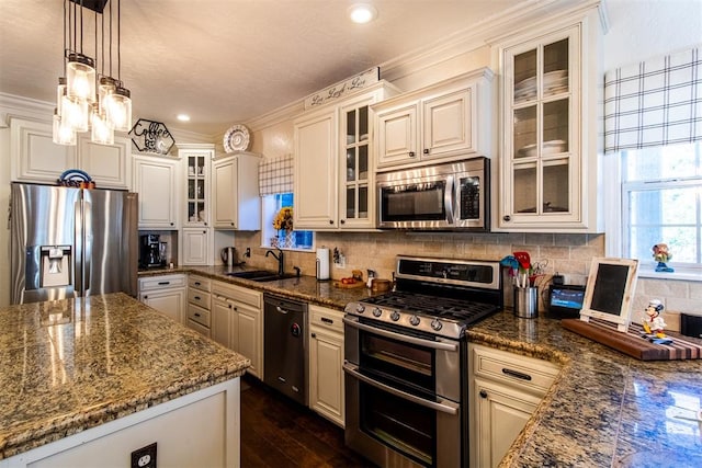 kitchen with dark stone counters, sink, stainless steel appliances, and decorative light fixtures