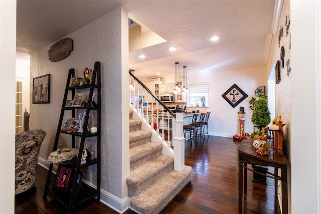 staircase with ornamental molding, a textured ceiling, and hardwood / wood-style flooring