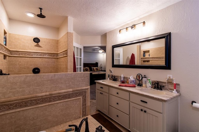 bathroom featuring a tile shower, ceiling fan, tile patterned floors, a textured ceiling, and vanity