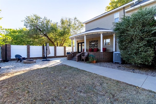 view of yard featuring covered porch, central AC unit, and an outdoor fire pit