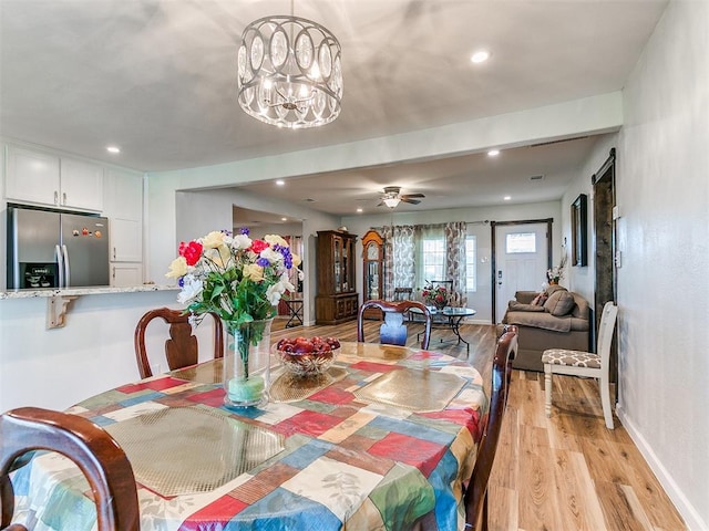 dining area featuring light hardwood / wood-style floors and ceiling fan with notable chandelier