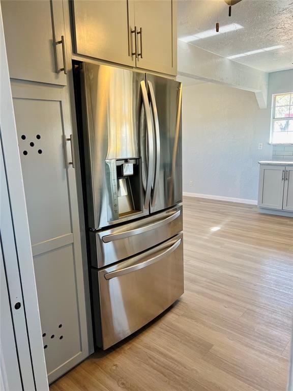 kitchen featuring stainless steel refrigerator with ice dispenser, a textured ceiling, and light hardwood / wood-style floors