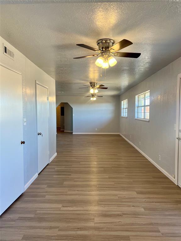 unfurnished room featuring ceiling fan, wood-type flooring, and a textured ceiling