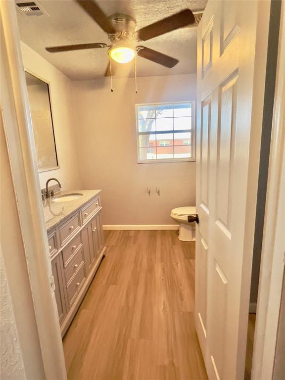 bathroom with hardwood / wood-style flooring, vanity, ceiling fan, and toilet