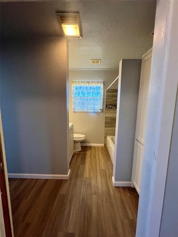 full bathroom featuring washtub / shower combination, vanity, hardwood / wood-style flooring, and toilet