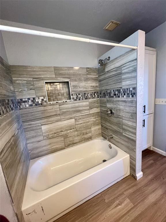 bathroom featuring wood-type flooring and tiled shower / bath