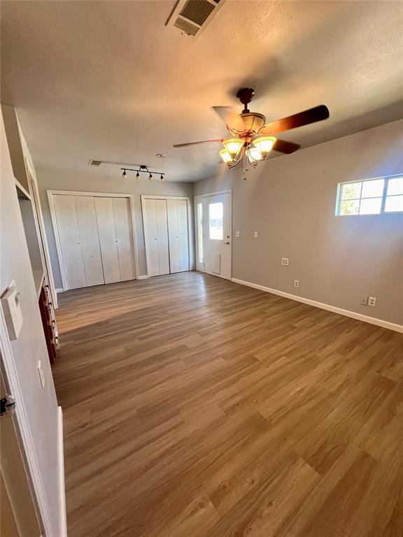 unfurnished bedroom featuring multiple closets, multiple windows, dark wood-type flooring, and ceiling fan