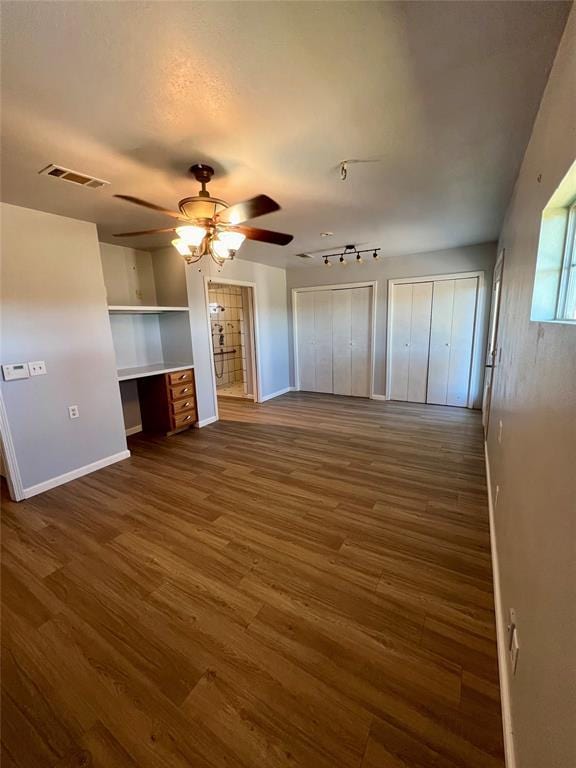 unfurnished living room with dark hardwood / wood-style flooring, ceiling fan, and built in desk