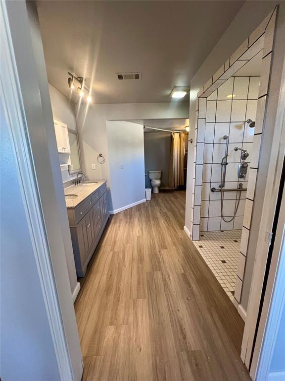 bathroom with a shower, toilet, vanity, and hardwood / wood-style flooring