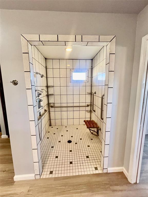 bathroom featuring wood-type flooring and tiled shower