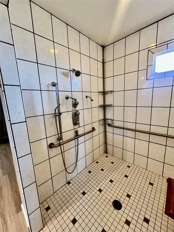 bathroom featuring hardwood / wood-style floors and a tile shower