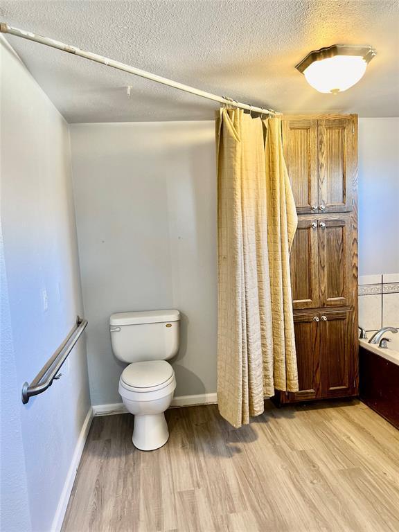 bathroom with independent shower and bath, wood-type flooring, a textured ceiling, and toilet