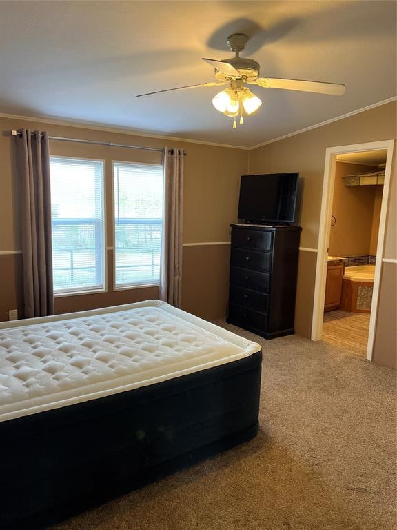 unfurnished bedroom featuring lofted ceiling, light carpet, ensuite bathroom, ceiling fan, and ornamental molding