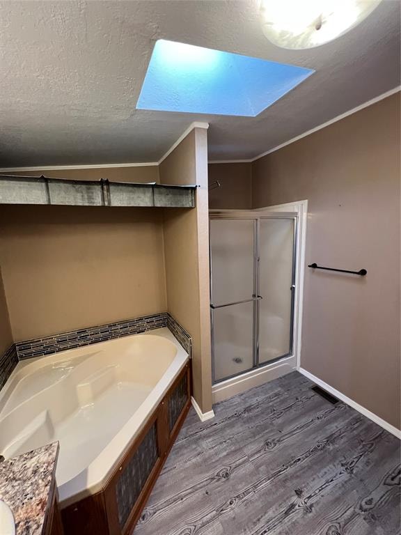 bathroom featuring plus walk in shower, hardwood / wood-style floors, a skylight, and crown molding