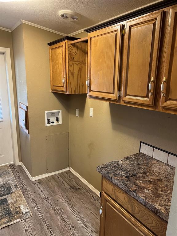 washroom featuring crown molding, dark wood-type flooring, cabinets, and washer hookup