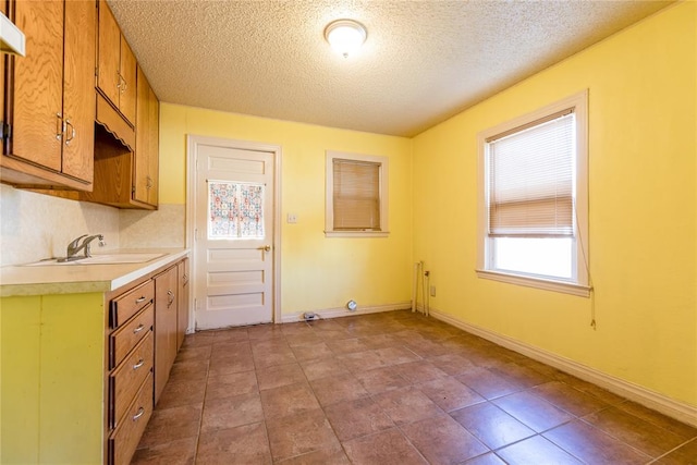 kitchen with sink, light tile patterned floors, and a textured ceiling