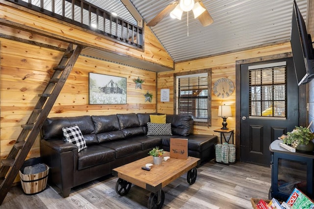 living room with vaulted ceiling with beams, hardwood / wood-style flooring, ceiling fan, and wood walls