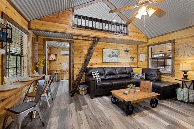 living room with hardwood / wood-style floors, ceiling fan, high vaulted ceiling, and wooden walls