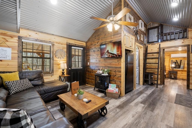 living room with wooden walls, high vaulted ceiling, wood-type flooring, and ceiling fan