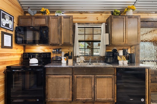 kitchen with sink, wood walls, and black appliances