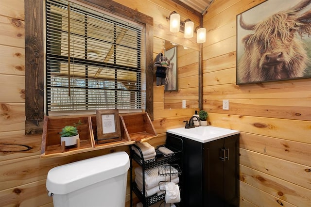 bathroom featuring vanity, toilet, and wooden walls