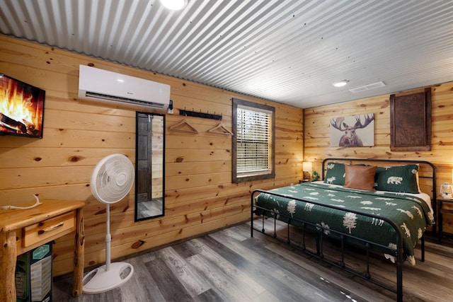 bedroom with hardwood / wood-style floors, a wall unit AC, and wood walls