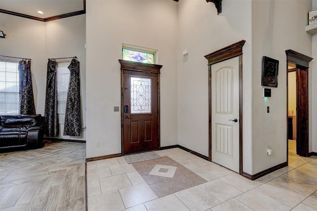 entryway with crown molding and a high ceiling