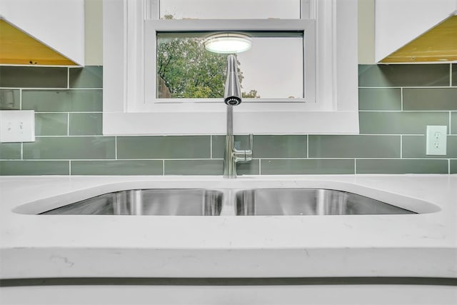 details featuring white cabinets, backsplash, and sink