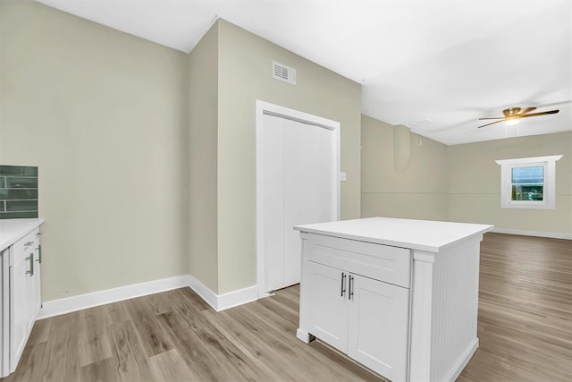 kitchen featuring white cabinets, a center island, light hardwood / wood-style floors, and ceiling fan