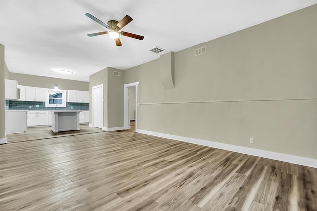 unfurnished living room featuring ceiling fan and light wood-type flooring