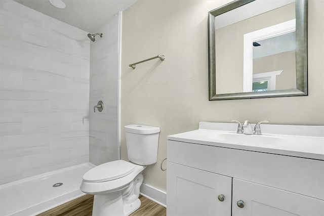 bathroom with tiled shower, vanity, wood-type flooring, and toilet