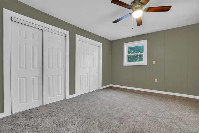 unfurnished bedroom featuring multiple closets, ceiling fan, and carpet